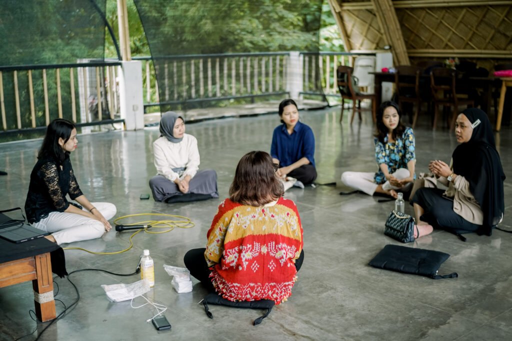 The founder of talk mental health sitting on the ground in a round circle with 5 other beneficiaries